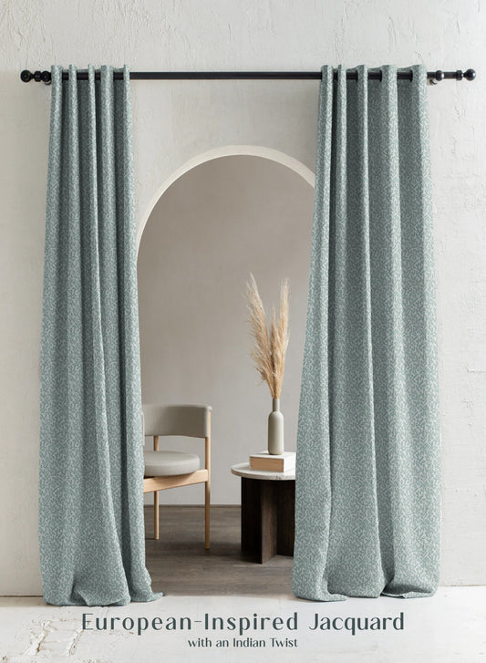 Light gray curtains hanging in a room with a chair and decor.